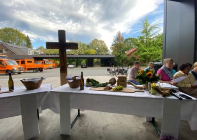 Gabentisch mit Kreuz, Sonnenblumen und singenden Teilnehmenden